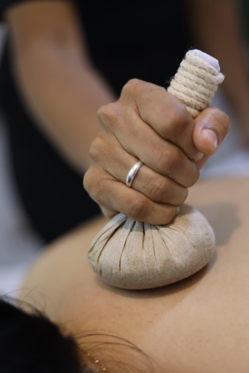 Therapist performing a traditional kizhi herbal pouch massage